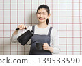 A smiling woman brewing coffee - a lifestyle image of daily life and housework. 139533590