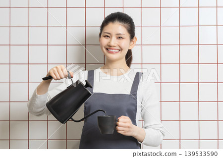 一位微笑的女士正在煮咖啡——展現日常生活和家務的畫面。 一位微笑的女士正在煮咖啡——展現日常生活和家務的畫面。 139533590