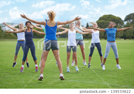Jumping jacks, women and group outdoor for exercise on sports field and energy for cardio in fitness class. Health, wellness and training together, athlete team workout in park and physical activity 139533622
