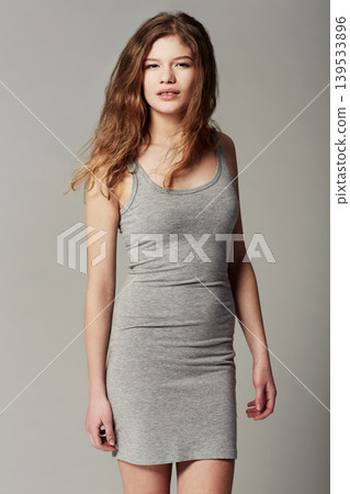Fashion, smile and portrait of woman in a studio with stylish, trendy and cool dress outfit. Confident, natural and young beautiful female model with casual style isolated by gray background. Fashion, smile and portrait of woman in a studio with stylish, trendy and cool dress outfit. Confident, natural and young beautiful female model with casual style isolated by gray background. 139533896