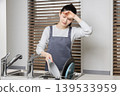 A woman experiencing shoulder stiffness and fatigue from housework; image of doing housework involving water. 139533959