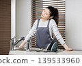 A woman experiencing shoulder stiffness and fatigue from housework; image of doing housework involving water. 139533960