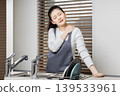 A woman experiencing shoulder stiffness and fatigue from housework; image of doing housework involving water. 139533961