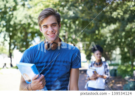 College, student and portrait of happy man on campus to study on scholarship for education. University, academy and person with book, headphones and walking with smile in park at school after class College, student and portrait of happy man on campus to study on scholarship for education. University, academy and person with book, headphones and walking with smile in park at school after class 139534124