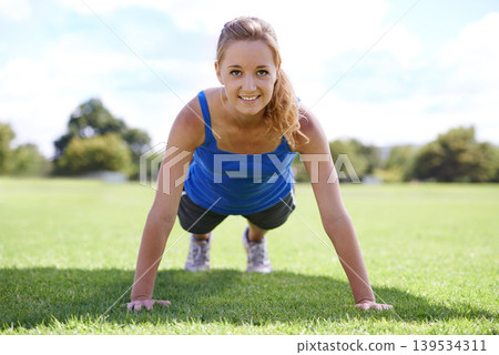 Women, face and push ups on grass for fitness with exercise, training and workout on sports field. Athlete, person and confidence on ground with physical activity for healthy body or wellness outdoor Women, face and push ups on grass for fitness with exercise, training and workout on sports field. Athlete, person and confidence on ground with physical activity for healthy body or wellness outdoor 139534311