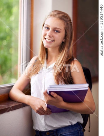 Happy woman, portrait and student with book at school hallway for education, study or learning. Young female person or teenager smile with textbooks and backpack for academic studying or knowledge 139534440