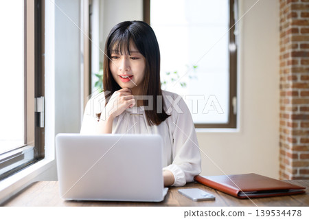 在辦公室使用筆記型電腦的年輕女商人 在辦公室使用筆記型電腦的年輕女商人 139534478