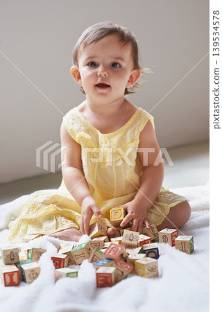 Baby, girl and toddler, blocks as toys for learning, playing at home for education and alphabet. Growth, early childhood development and young kid with educational activity, playtime and montessori Baby, girl and toddler, blocks as toys for learning, playing at home for education and alphabet. Growth, early childhood development and young kid with educational activity, playtime and montessori 139534578