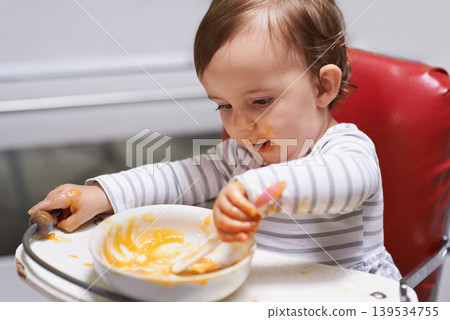 Kid eating, high chair and food, nutrition and health for childhood development and wellness. Healthy, growth and toddler person at home, vegetable or fruit, hungry baby with lunch or dinner meal Kid eating, high chair and food, nutrition and health for childhood development and wellness. Healthy, growth and toddler person at home, vegetable or fruit, hungry baby with lunch or dinner meal 139534755