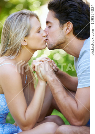 Couple, kiss and holding hands in park with love and commitment in healthy relationship. People on a date outdoor, affection and care with trust, partner and bonding together for marriage and romance Couple, kiss and holding hands in park with love and commitment in healthy relationship. People on a date outdoor, affection and care with trust, partner and bonding together for marriage and romance 139534824