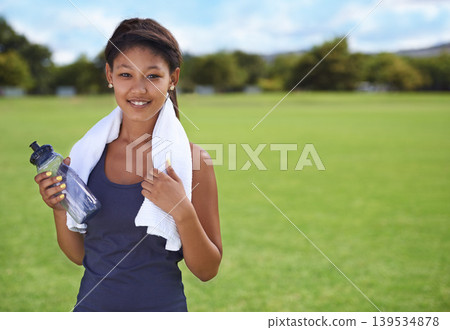 Woman, portrait and water bottle in fitness on green grass for workout, exercise or outdoor training. Face of female person or athlete with towel, drink or mineral liquid for natural sustainability Woman, portrait and water bottle in fitness on green grass for workout, exercise or outdoor training. Face of female person or athlete with towel, drink or mineral liquid for natural sustainability 139534878
