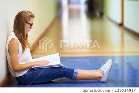 Woman, teenager and student reading book in hallway at school for learning, education or studying. Female person or young child or kid sitting on floor in corridor with textbook outside classroom 139534917