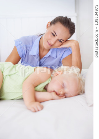 Love, sleeping and mother with baby on bed for bonding, relax and sweet cute relationship. Happy, smile and young mom watching girl child, kid or toddler taking a nap in bedroom or nursery at home. Love, sleeping and mother with baby on bed for bonding, relax and sweet cute relationship. Happy, smile and young mom watching girl child, kid or toddler taking a nap in bedroom or nursery at home. 139534975