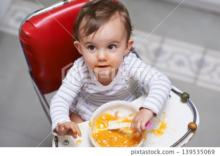 Child eating, high chair and food, nutrition and health for childhood development and wellness. Healthy, growth and toddler person at home, vegetable or fruit, hungry baby with lunch or dinner meal Child eating, high chair and food, nutrition and health for childhood development and wellness. Healthy, growth and toddler person at home, vegetable or fruit, hungry baby with lunch or dinner meal 139535069