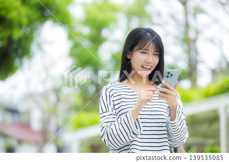 操作智能手機的一個少婦戶外 139535085