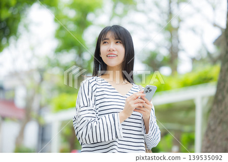 操作智能手機的一個少婦戶外 操作智能手機的一個少婦戶外 139535092