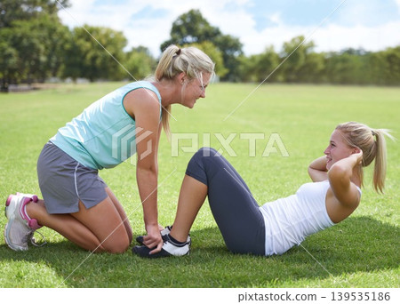 Woman, personal trainer and sit ups for fitness, workout or outdoor exercise together on green grass. Young active female person or coach for core strength, training or motivation on field in nature Woman, personal trainer and sit ups for fitness, workout or outdoor exercise together on green grass. Young active female person or coach for core strength, training or motivation on field in nature 139535186