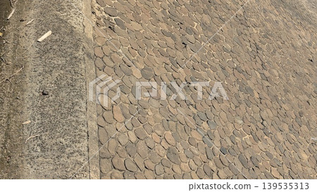 Detailed texture of stone dam wall construction, brown rock masonry surface under bright sunlight, solid outdoor infrastructure material, rural water management structure, natural stone pattern. 139535313