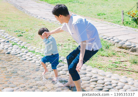 A parent and child playing in a summer stream A parent and child playing in a summer stream 139535337