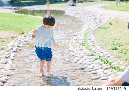 A parent and child playing in a summer stream 139535349