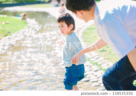 A parent and child playing in a summer stream 139535350