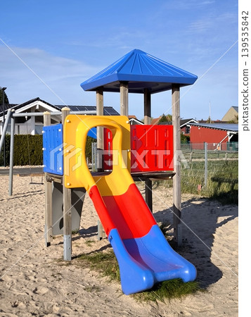 A bright children's slide at a sandy playground on a sunny day A bright children's slide at a sandy playground on a sunny day 139535842