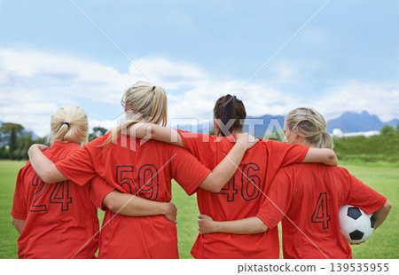 Woman, back and hug in soccer of sports team ready for match, game or outdoor practice with blue sky. Rear view of female person or group of football players standing in unity with ball in nature Woman, back and hug in soccer of sports team ready for match, game or outdoor practice with blue sky. Rear view of female person or group of football players standing in unity with ball in nature 139535955