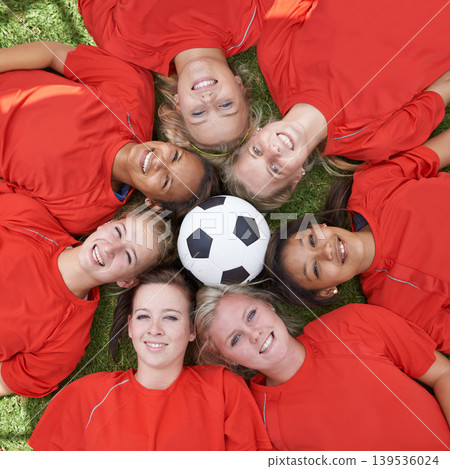 Happy woman, soccer ball and face of team above for unity, collaboration or synergy lying on green grass. Top view or portrait of female person, group or football players smile on outdoor field Happy woman, soccer ball and face of team above for unity, collaboration or synergy lying on green grass. Top view or portrait of female person, group or football players smile on outdoor field 139536024