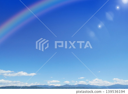 A peaceful rural backdrop featuring a clear blue sky with a few clouds, a rainbow, and a range of mountains. A peaceful rural backdrop featuring a clear blue sky with a few clouds, a rainbow, and a range of mountains. 139536194