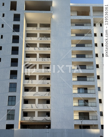 Abstract architectural facade with repetitive window pattern and geometric shapes in urban setting Abstract architectural facade with repetitive window pattern and geometric shapes in urban setting 139536361