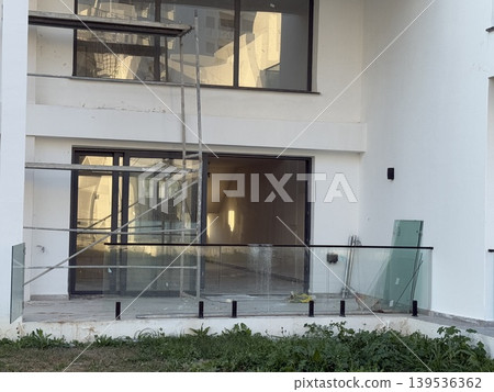 Construction site with unfinished modern building facade and outdoor glass railing Construction site with unfinished modern building facade and outdoor glass railing 139536362