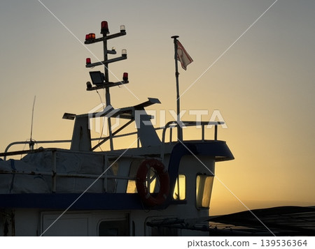 Boat silhouette against sunset sky with Canadian flag, suitable for travel or nautical themes 139536364