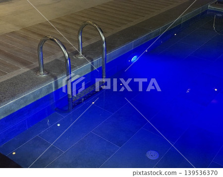Illuminated pool at night with blue lighting creates serene and calming background atmosphere Illuminated pool at night with blue lighting creates serene and calming background atmosphere 139536370