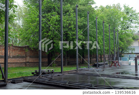 Row of vertical steel pillars at an outdoor construction site for a new industrial building or warehouse frame. Row of vertical steel pillars at an outdoor construction site for a new industrial building or warehouse frame. 139536616