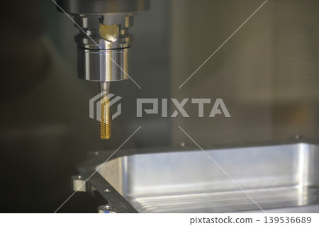 Close-up of a special-purpose tapping tool during the high-precision internal thread-making process for automotive parts. 139536689