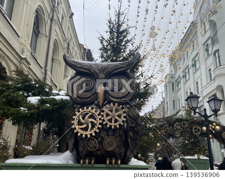 Owl sculpture decorated with gears in festive street during winter holiday season Owl sculpture decorated with gears in festive street during winter holiday season 139536906