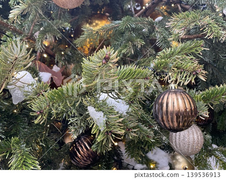 Christmas tree branches adorned with gold and bronze ornaments and twinkling lights background Christmas tree branches adorned with gold and bronze ornaments and twinkling lights background 139536913