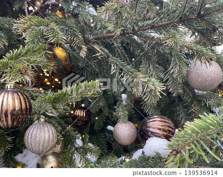 Christmas tree branches adorned with festive ornaments and lights, ideal for holiday background Christmas tree branches adorned with festive ornaments and lights, ideal for holiday background 139536914