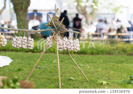 Garlic hanging on a wooden stand in a garden during a market event in an outdoor setting in the afternoon Garlic hanging on a wooden stand in a garden during a market event in an outdoor setting in the afternoon 139536970