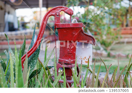 Weathered red water pump in outdoor garden 139537005