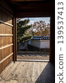 Pine trees and white walls visible from the doorway of a traditional Japanese house. 139537413