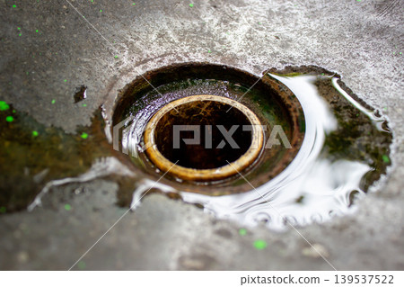 Cement sink drainage hole with clear water and light reflection. 139537522
