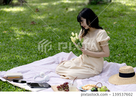Beautiful young woman in a summer dress holding a bouquet Beautiful young woman in a summer dress holding a bouquet 139537602