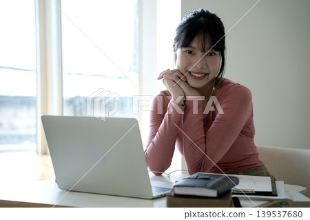 Young woman smiling sitting at her desk and talking on the phone Young woman smiling sitting at her desk and talking on the phone 139537680