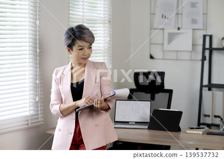 Senior businesswoman relaxing at desk in office while taking a break Senior businesswoman relaxing at desk in office while taking a break 139537732