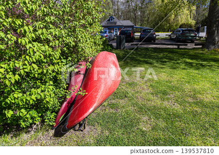 Red canoe on green grass near lakeside recreation area in Denmark. Red canoe on green grass near lakeside recreation area in Denmark. 139537810