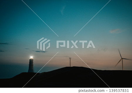 A lighthouse and wind turbines at dusk A lighthouse and wind turbines at dusk 139537831