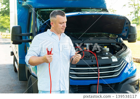 Confused driver with jumper cables near open hood Confused driver with jumper cables near open hood 139538117