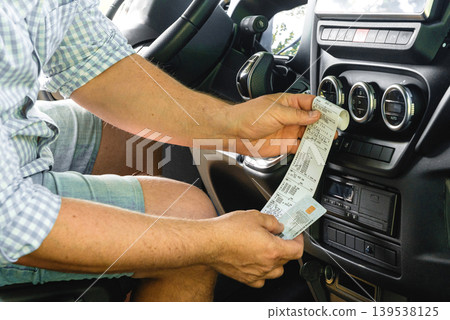Truck driver checking digital tachograph paper printout Truck driver checking digital tachograph paper printout 139538125