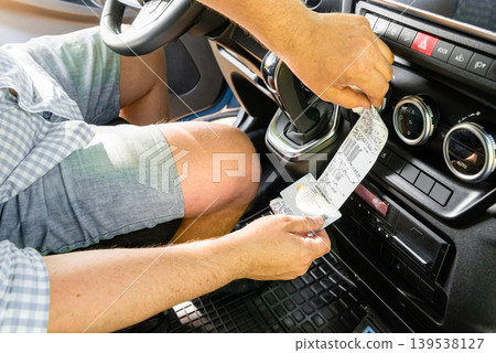 Driver holding long tachograph paper in truck cab Driver holding long tachograph paper in truck cab 139538127